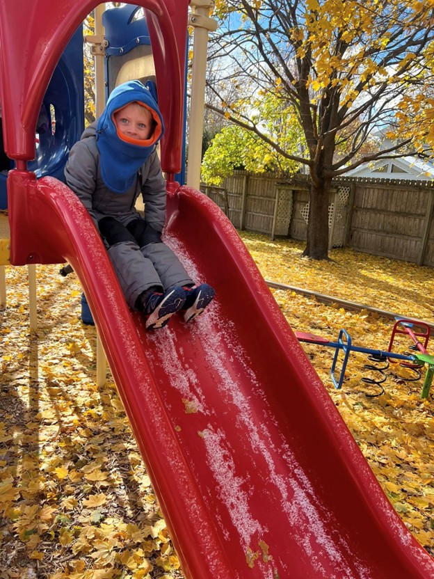 Child enjoying the playground slide in fall